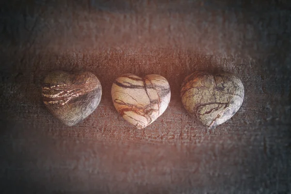 Drie stenen harten op hout — Stockfoto