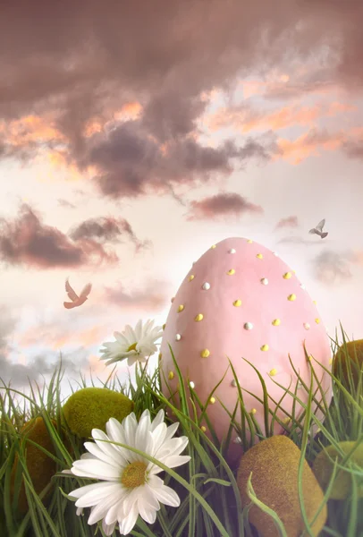 Велике рожеве яйце з квітами у високій траві — стокове фото