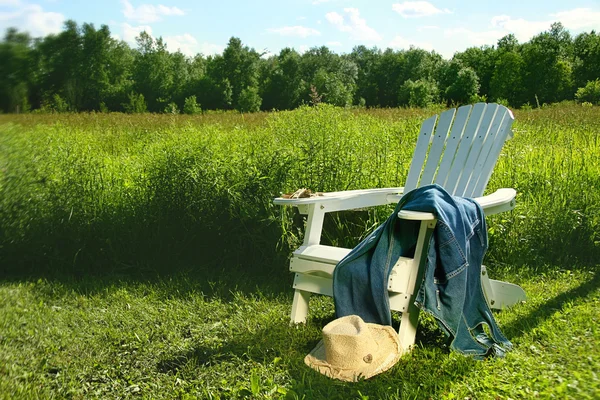 Jeans laying on adirondack chair in field — Stock Photo, Image