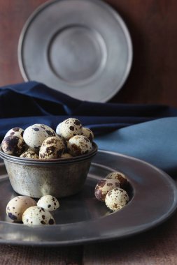 Ahşap masada bıldırcın yumurtalı kalay tabaklar.