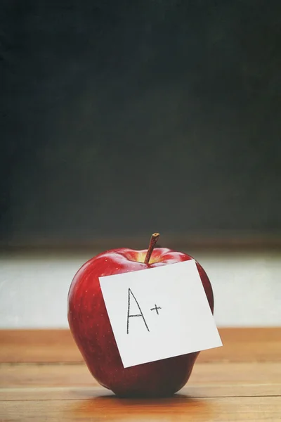 Red apple with note on desk with blackboard — Stock Photo, Image