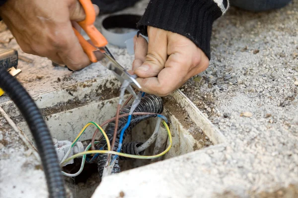 Elettricista controlla cavo elettrico esterno — Foto Stock