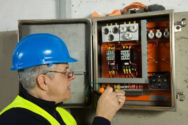 Eletricista sênior verificar o painel elétrico — Fotografia de Stock