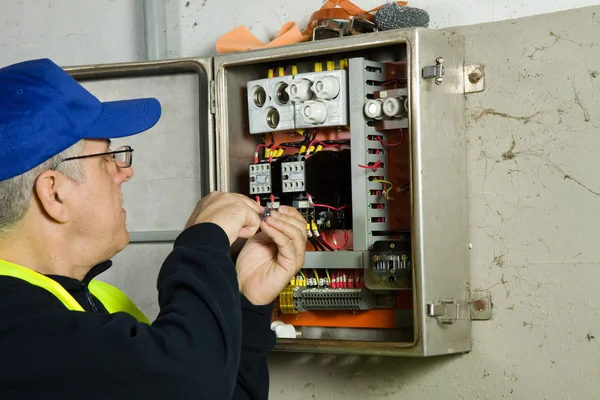 Eletricista sênior verificar o painel elétrico — Fotografia de Stock