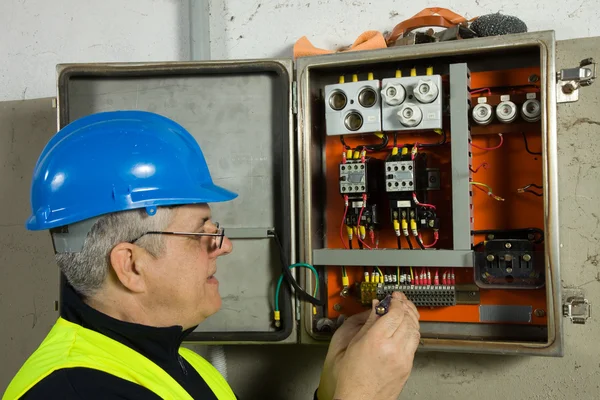 Electricista senior revisa el panel eléctrico —  Fotos de Stock