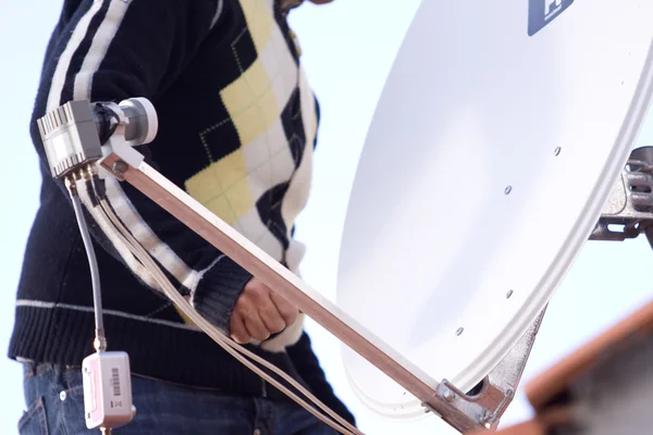 L'homme fixe une antenne parabolique — Photo