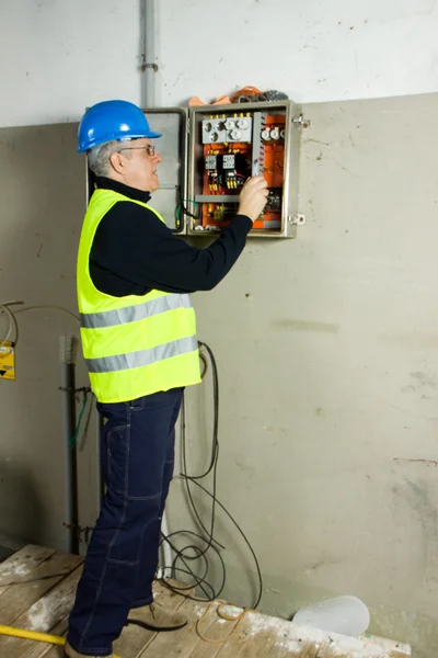 Eletricista sênior verificar o painel elétrico — Fotografia de Stock