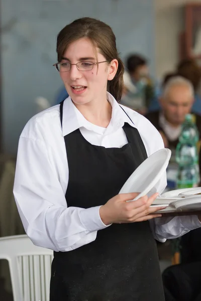 Serveerster draagt een dienblad met platen — Stockfoto