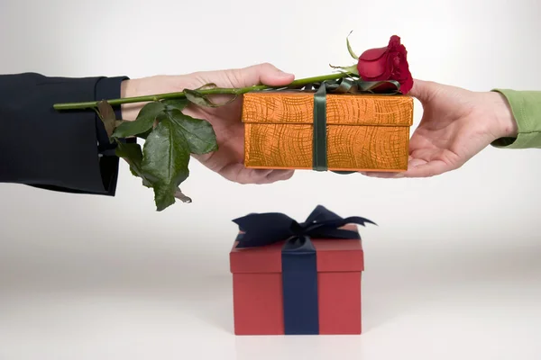 Man's hand gives rose and gift — Stock Photo, Image