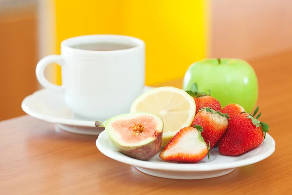 Φλιτζάνι τσάι, μπισκότο, μήλο, λεμόνι, σύκο και φράουλες σε ένα πιάτο — Φωτογραφία Αρχείου