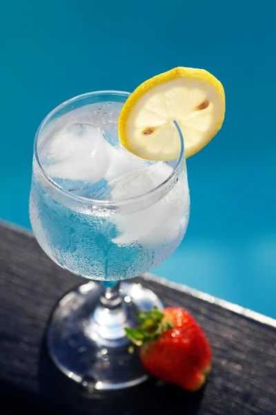 Swimming pool, lounge, a wine glass with ice, lemon and strawber — Stock Photo, Image