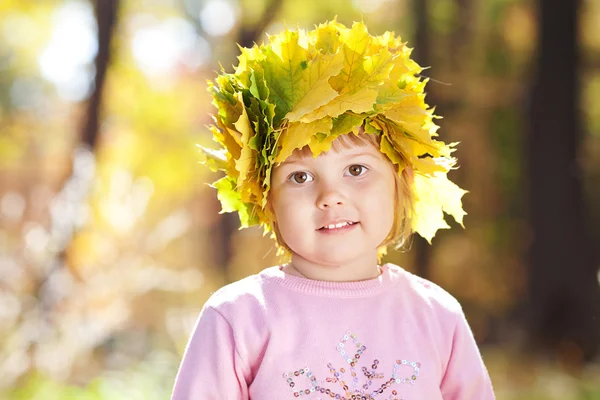 Красива маленька дівчинка в вінок з кленових листя восени на передньому плані — стокове фото