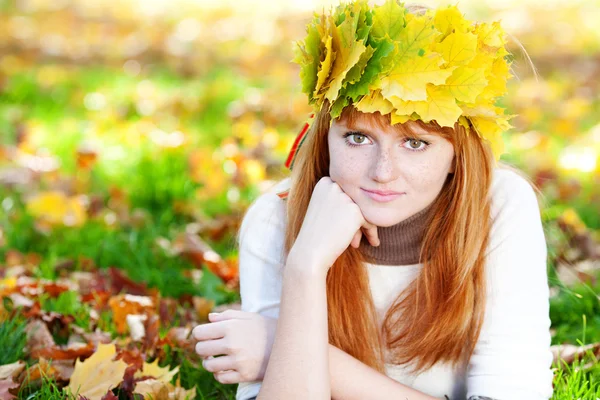 Giovane donna adolescente rossa in una ghirlanda di foglie d'acero sdraiato o — Foto Stock