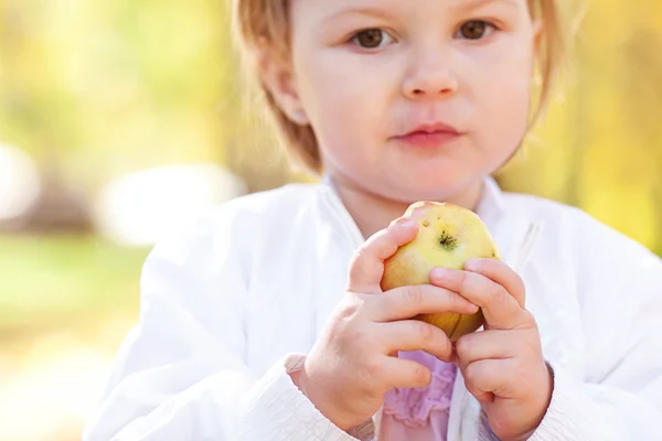 Linda menina comendo maçã na floresta de outono — Fotografia de Stock