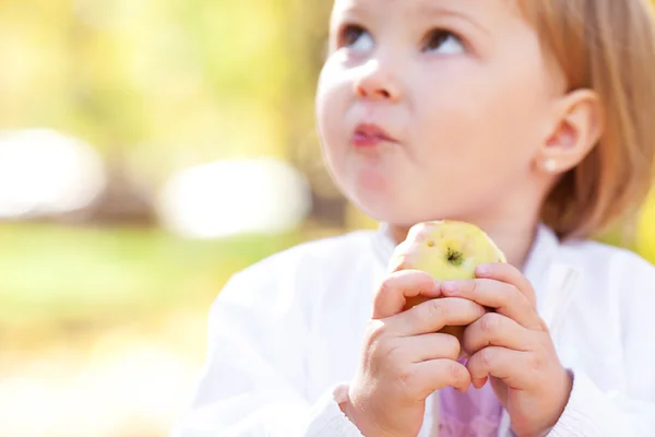 Linda menina comendo maçã na floresta de outono — Fotografia de Stock