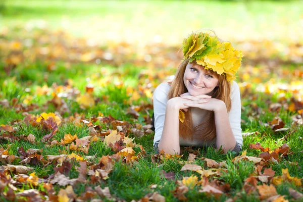 Jovem ruiva adolescente mulher em uma grinalda de folhas de bordo deitado o — Fotografia de Stock