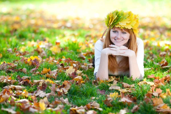 Joven pelirroja adolescente mujer en una corona de hojas de arce mintiendo o — Foto de Stock