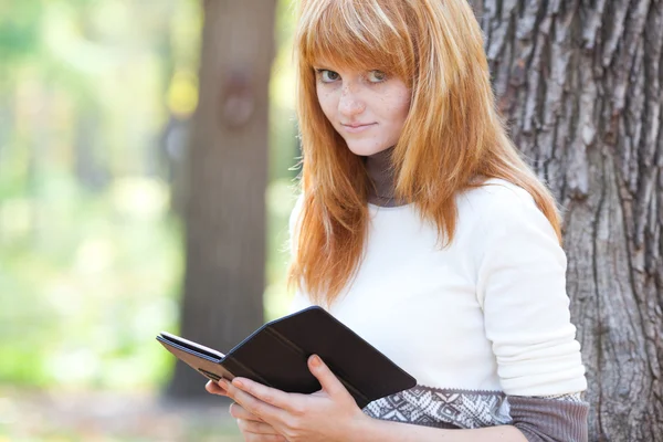 Portrait of a beautiful young redhead teenager woman reading a b — Stock Photo, Image