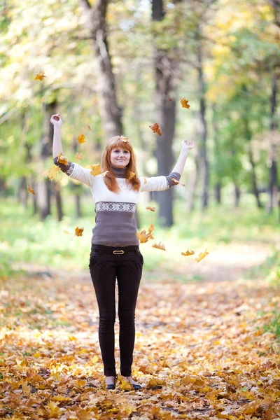 Joven pelirroja adolescente lanzando hojas mujer en el bosque — Foto de Stock