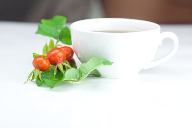 fincan çay ve kuşburnu yaprakları beyaz zemin üzerine çilek