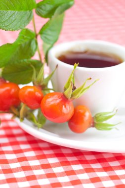 fincan çay ve kuşburnu yaprakları ekose kumaş ile çilek