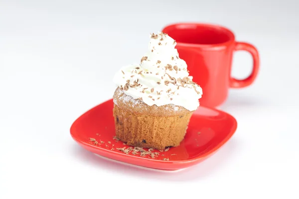 Muffin with whipped cream and red cup on white background — Stock Photo, Image