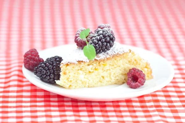 Cake with icing, raspberry, blackberry and mint on a plate on pl — Stock Photo, Image