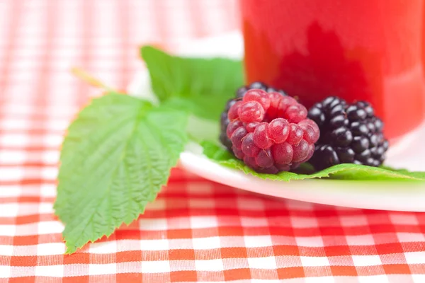 Cup of tea,raspberry and blackberry with leaves on plaid fabric — Stock Photo, Image