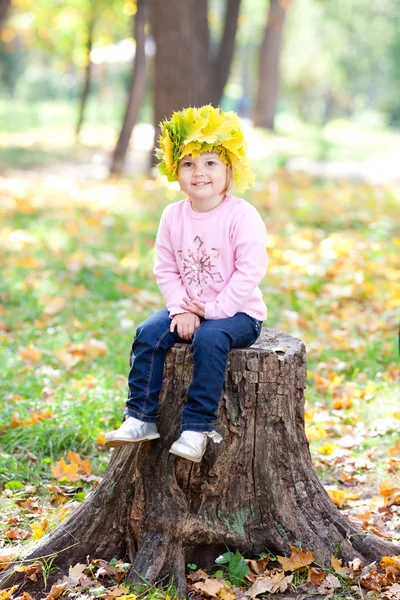 Bella bambina in una ghirlanda di foglie d'acero seduta su stu — Foto Stock