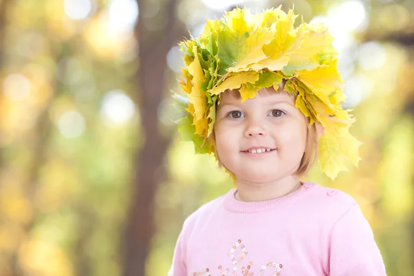 Красива маленька дівчинка в вінок з кленових листя восени на передньому плані — стокове фото