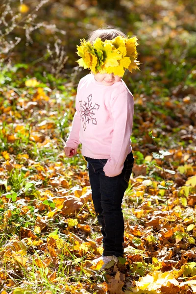 Bella bambina in una ghirlanda di foglie d'acero in autunno prima — Foto Stock
