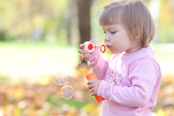 漂亮的小女孩制作泡沫鼓风机在秋天的森林 — 图库照片