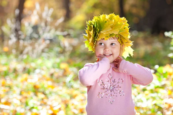 Belle petite fille dans une couronne de feuilles d'érable à l'automne avant — Photo