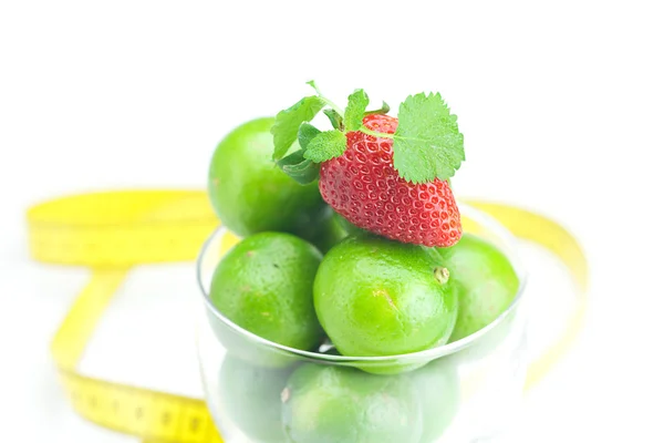 Citron vert dans une tasse en verre, ruban à mesurer, fraise et menthe isoler — Photo