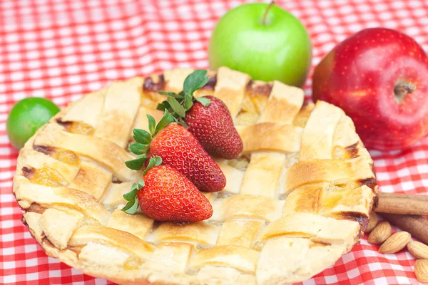 Torta de maçã, maçã, limão, canela e morango em tecido xadrez — Fotografia de Stock