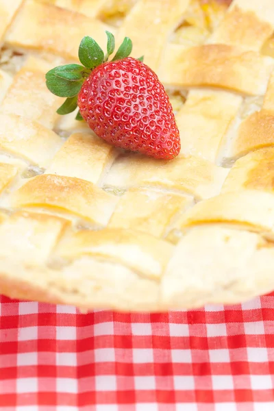 Apple pie and a strawberry on plaid fabric — Stock Photo, Image