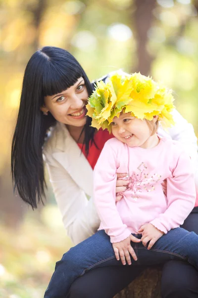 Vacker ung mamma håller sin dotter i en krans av lönn — Stockfoto