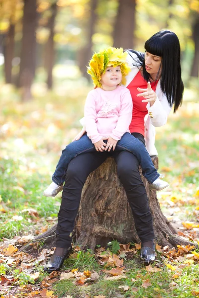 Vacker ung mamma håller sin dotter i en krans av lönn — Stockfoto