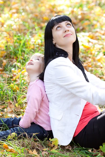 Hermosa joven madre y su hija mirando hacia arriba en el otoño — Foto de Stock