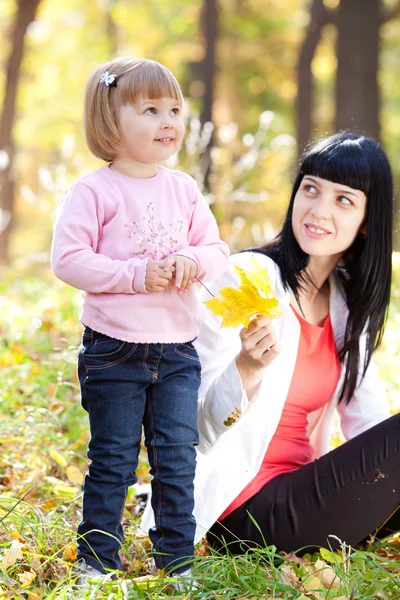 Mooie jonge moeder en haar dochter op het autumv-bos — Stockfoto