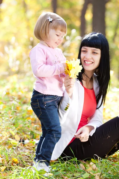 Vacker ung mamma och hennes dotter på autumv skogen — Stockfoto