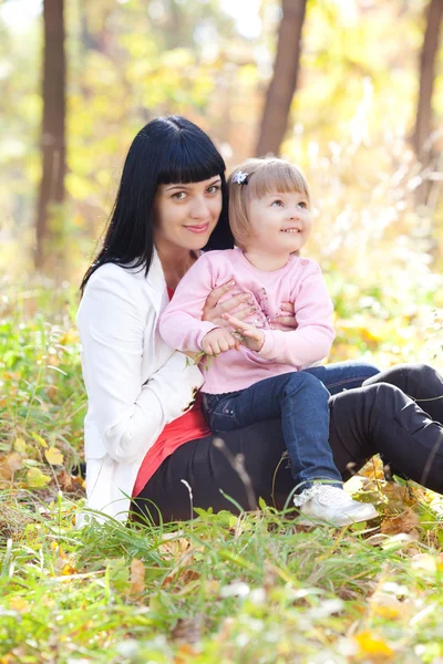 Vacker ung mamma och hennes dotter på autumv skogen — Stockfoto