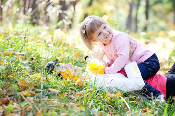 Vacker ung mamma och hennes dotter liggande på hösten lämn — Stockfoto