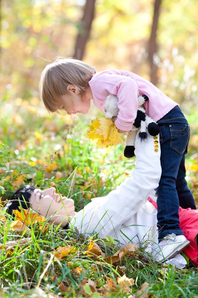 Schöne junge Mutter und ihre Tochter auf dem Herbstblatt liegend — Stockfoto