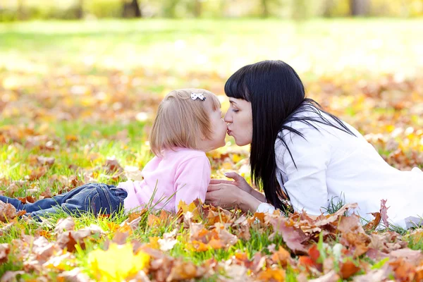 Mooie jonge moeder en haar dochter liggend op de herfst leav — Stockfoto