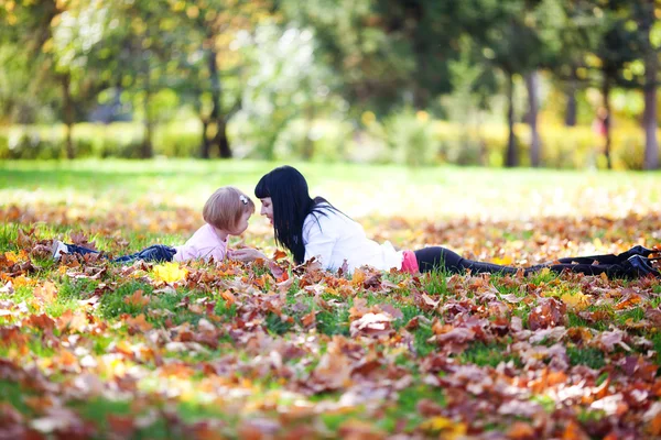 Piękna młoda matka z córką, leżącego na jesień leav — Zdjęcie stockowe