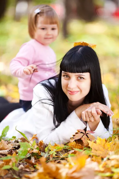 Beautiful young mother and her daughter lying on the autumn leav — Stock Photo, Image