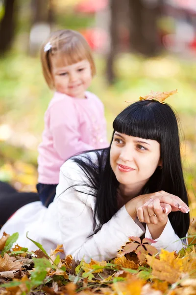 Hermosa joven madre y su hija acostada en el otoño leav —  Fotos de Stock