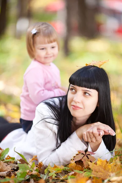 Krásná mladá matka a její dcera, ležící na podzimní op — Stock fotografie