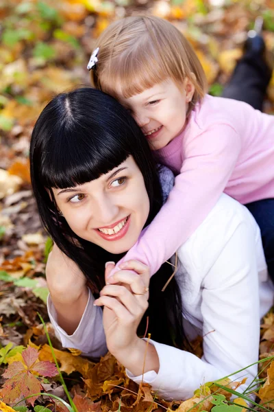 Bela jovem mãe e sua filha deitada no outono leav — Fotografia de Stock